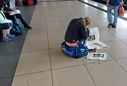 Frau liest Zeitung auf Bahnsteig