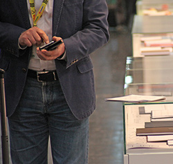 Mann mit Smartphone neben Notizbuchvitrine