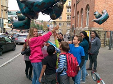 Frau verteilt Luftballons an Kinder